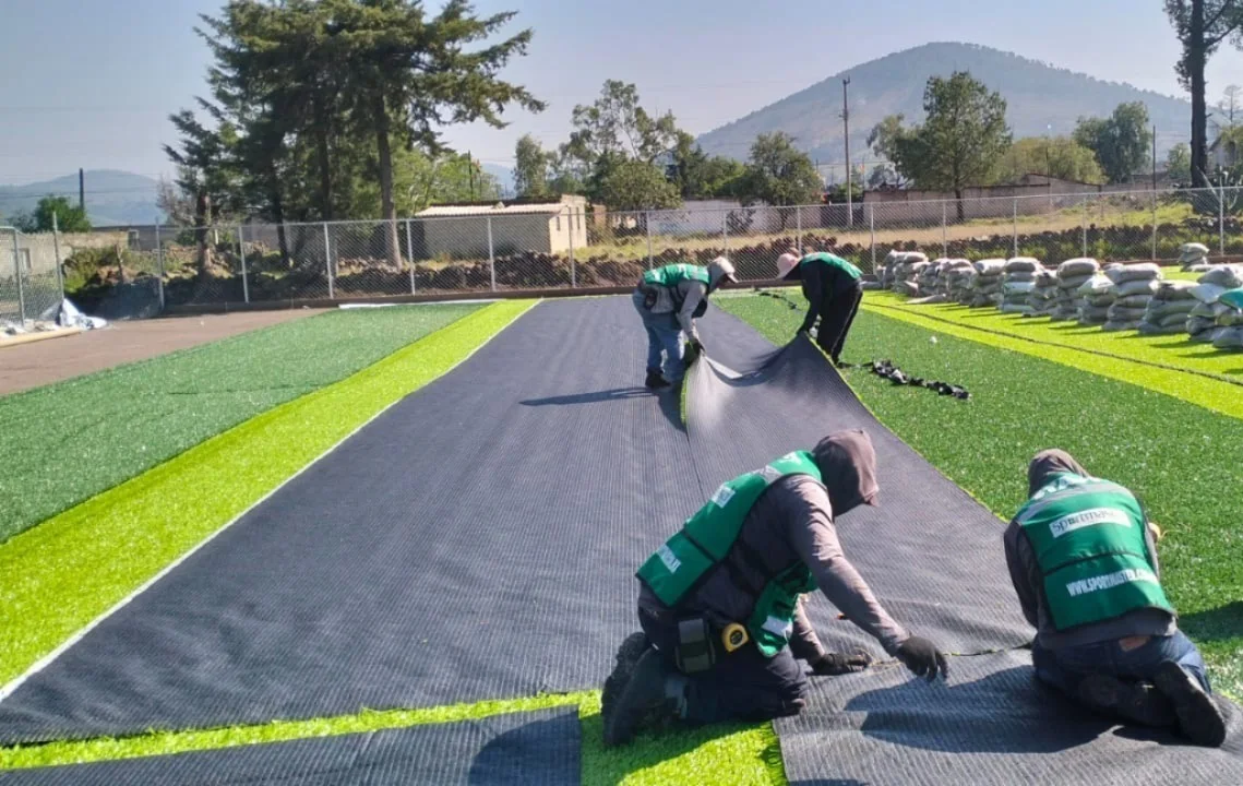 instaladores colocando rollos de pasto sintético sobre cancha