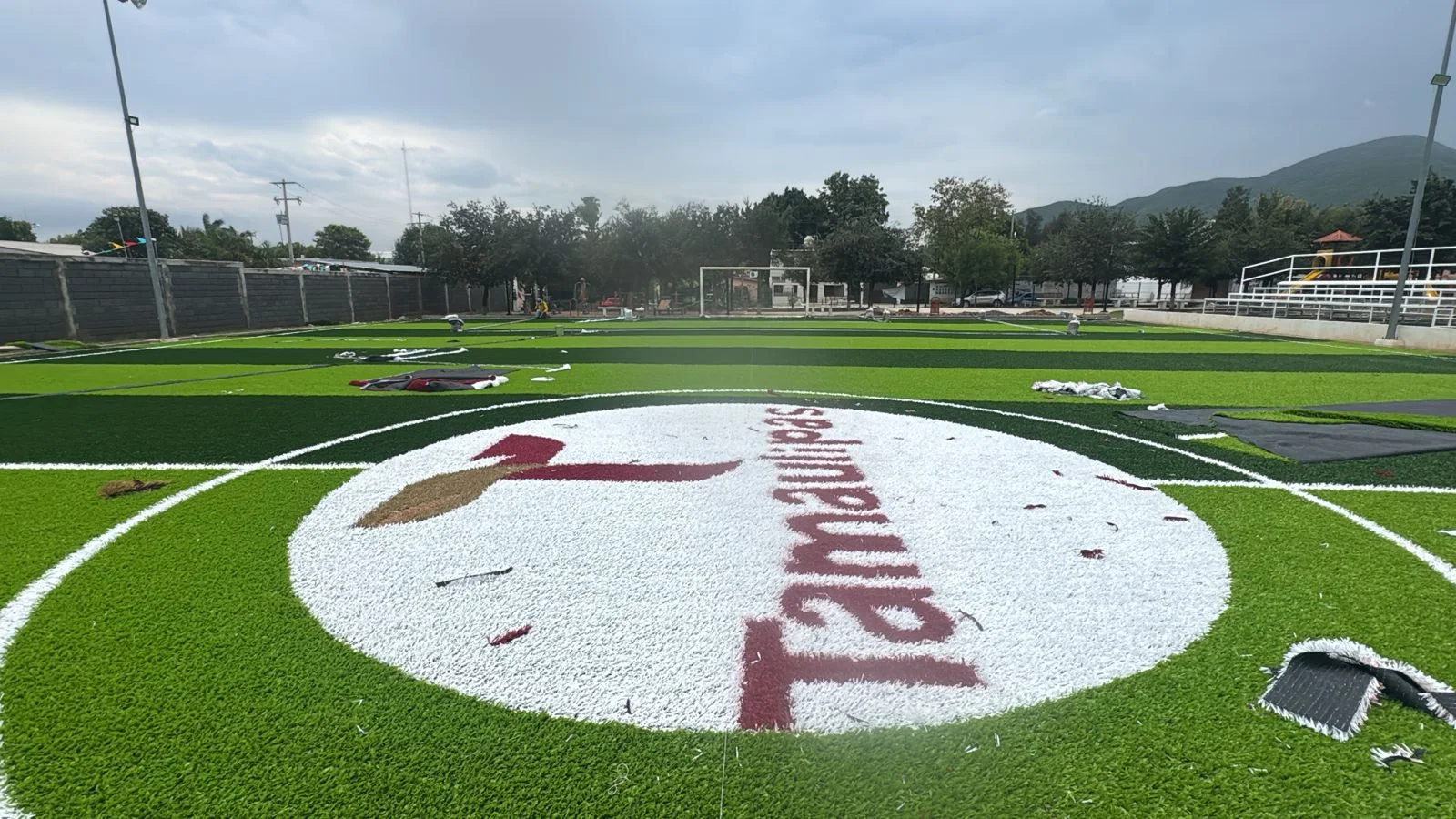 cancha de pasto sintético con logotipo y líneas deportivas