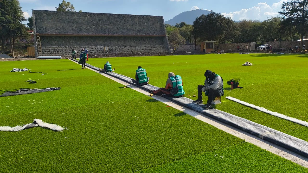 cuadrilla instalando pasto sintético en cancha deportiva