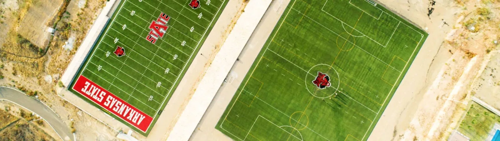 Vista aérea de la cancha de fútbol americano de Arkansas State University, campus Querétaro, con zona de anotación y logotipos personalizados en pasto sintético