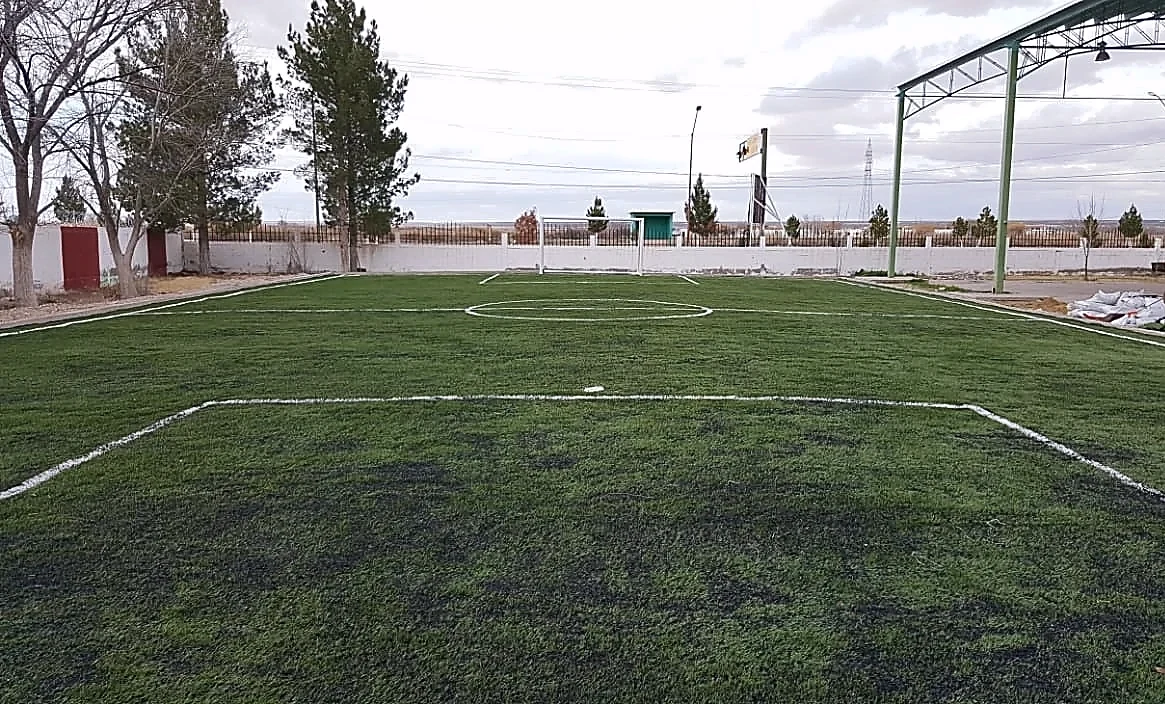 Cancha de fútbol 5 con pasto sintético en Secundaria Técnica #53, Praxedis G. Guerrero, Chihuahua: la cancha desde la línea lateral