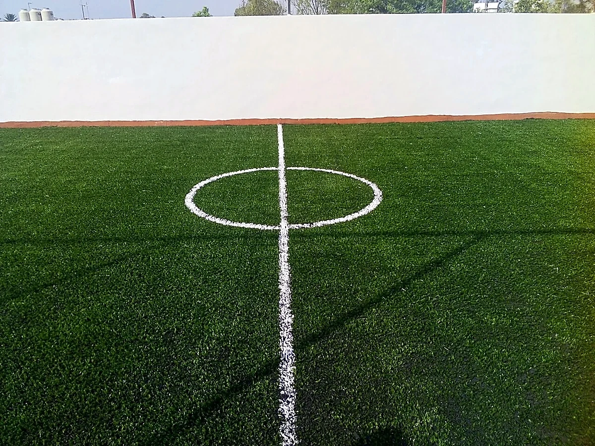 Cancha de fútbol 7 con pasto sintético en Colegio Aztlán, Tlalpan, Ciudad de México: la cancha desde la línea lateral