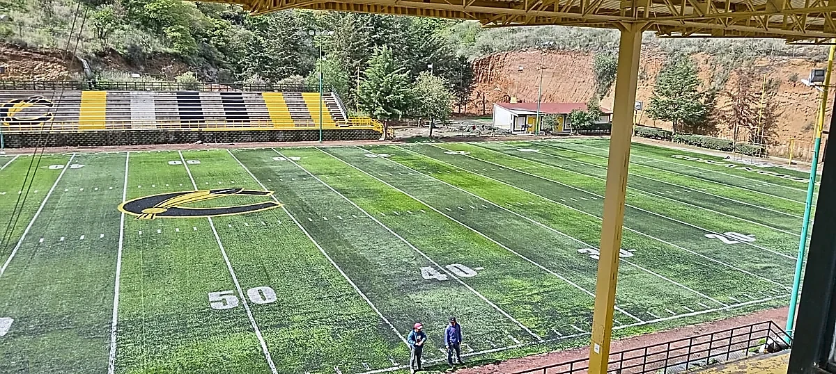 Campo de fútbol americano con pasto sintético visto desde la tribuna, con logotipo central y yarda 50, en Atizapán de Zaragoza
