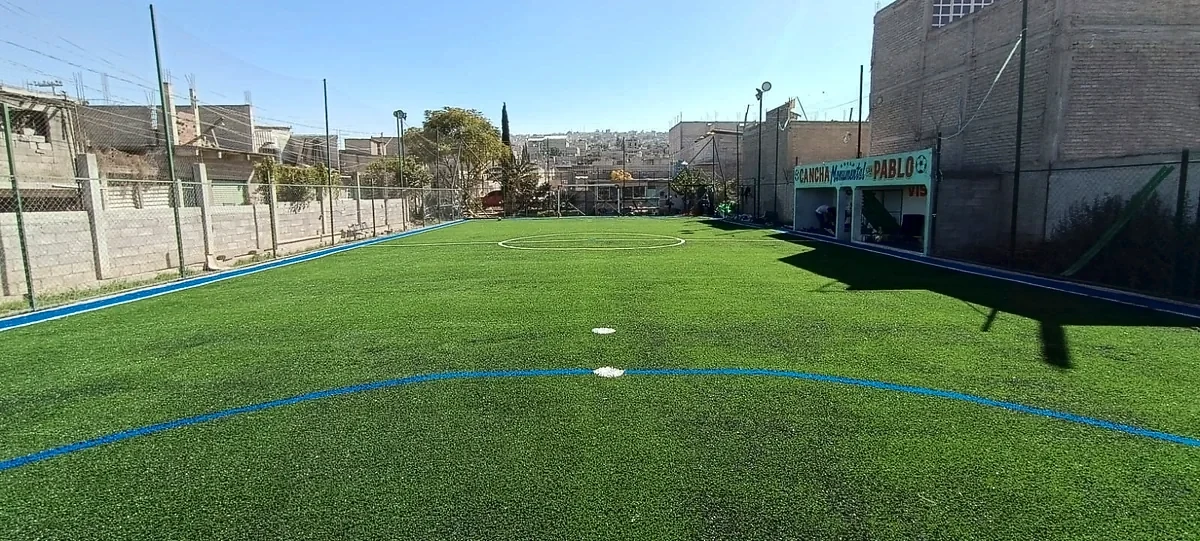 Cancha de fútbol 5 con pasto sintético en Cancha Monumental San Pablo, Chimalhuacán, Estado de México: la cancha desde la línea lateral