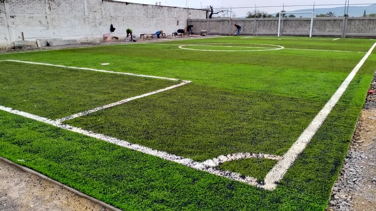 Cancha de fútbol 5 con pasto sintético en Instituto Magno Sección Preparatoria, Celaya, Guanajuato: la cancha desde la línea lateral