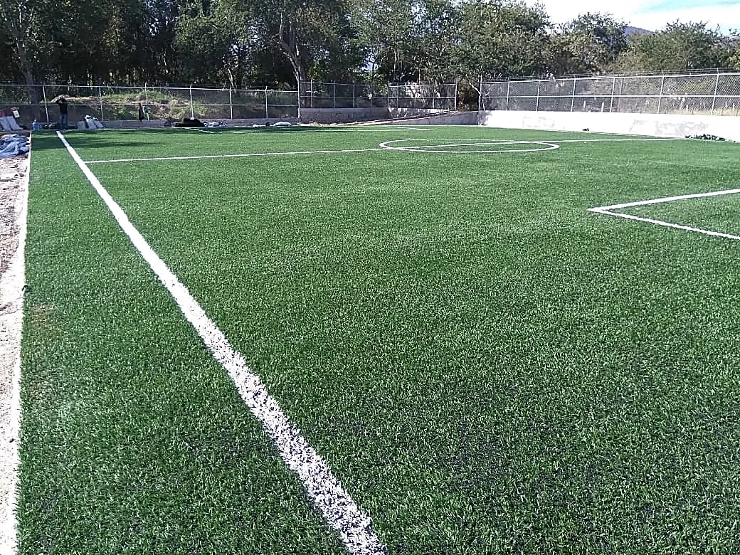 Cancha de fútbol 5 con pasto sintético en Campo Deportivo de Santa Cruz, Tixtla, Guerrero: la cancha desde la línea lateral
