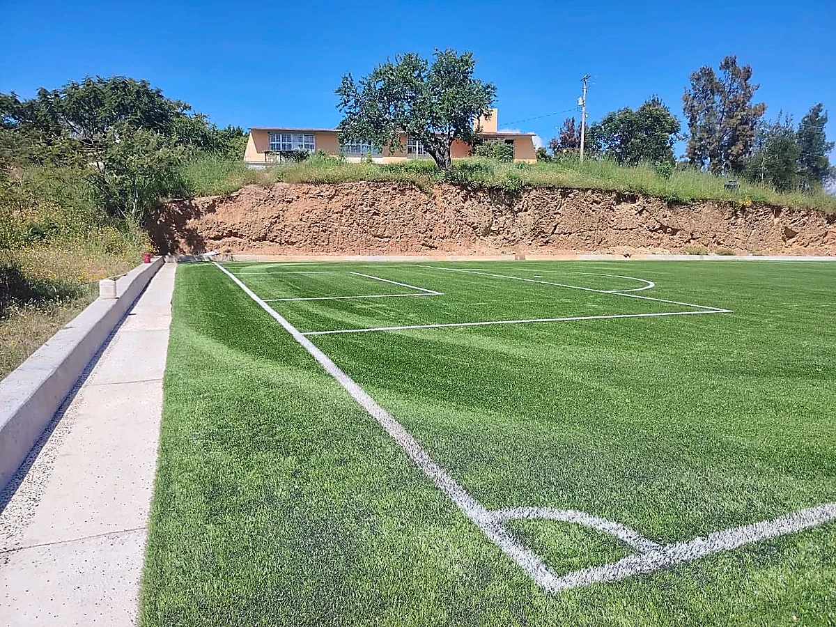 Cancha de fútbol 7 con pasto sintético en Escuela Primaria Bilingüe Emiliano Zapata, Temalacatzingo, Guerrero: pasto sintético deportivo recién cepillado