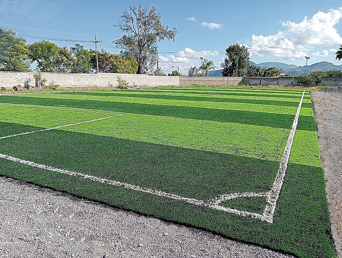 Cancha de fútbol 7 con pasto sintético en Escuela Secundaria Técnica Jesús Arizmendi Rogel, Pilcaya, Guerrero: pasto sintético deportivo recién cepillado