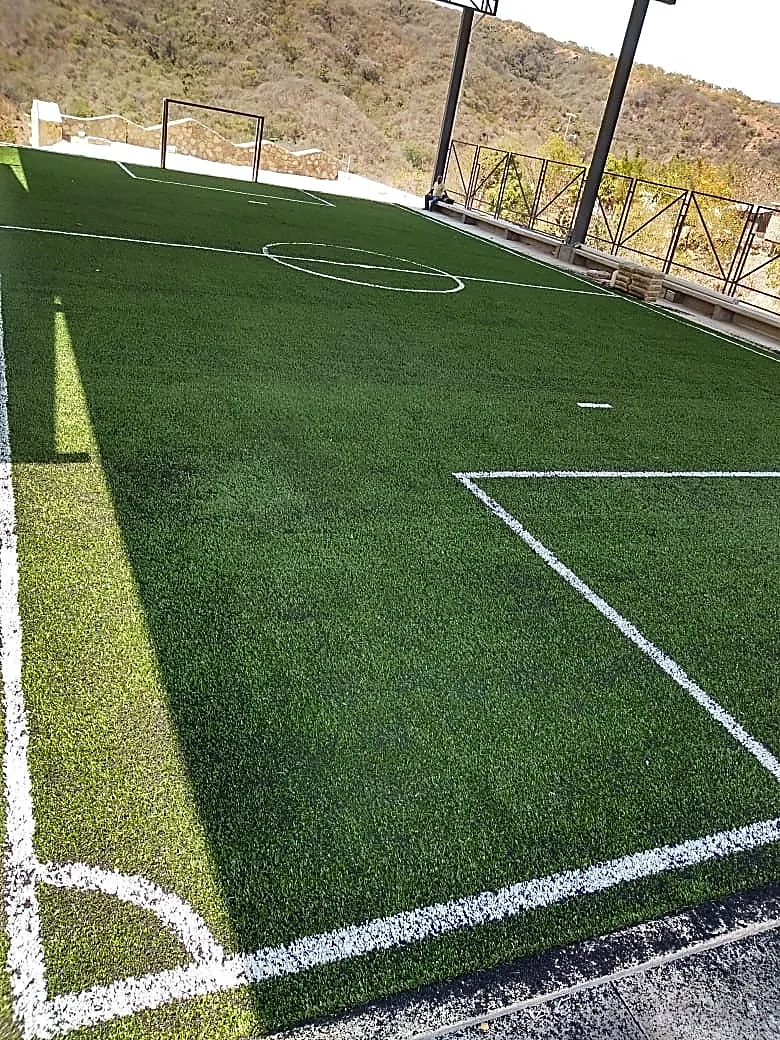 Cancha de fútbol 5 escolar con pasto sintético, líneas insertadas y portería en una telesecundaria de Acapulco