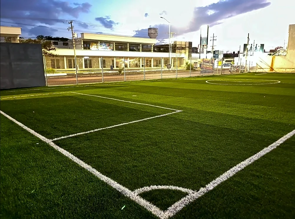 Cancha escolar de fútbol 7 con pasto sintético, área y arco de esquina insertados en el Colegio Rochavi Altabrisa, Mérida