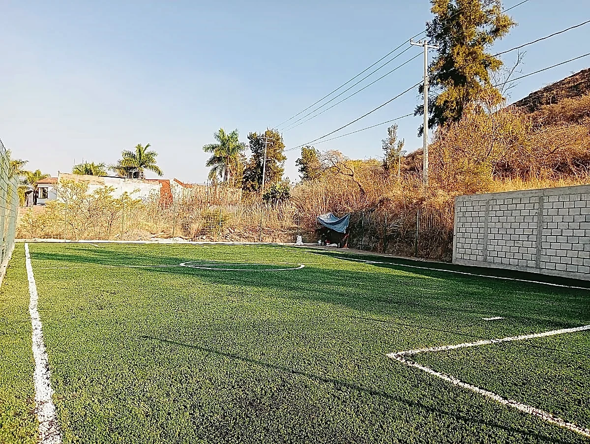 Cancha de fútbol 5 con pasto sintético en Escuela de Futbol Fénix, Zinapécuaro, Michoacán: la cancha desdel fondo