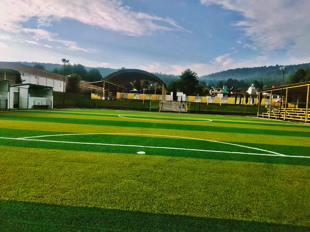 Cancha de fútbol 7 con pasto sintético en Complejo Deportivo Santa Clara del Cobre, Michoacán: pasto sintético deportivo recién cepillado