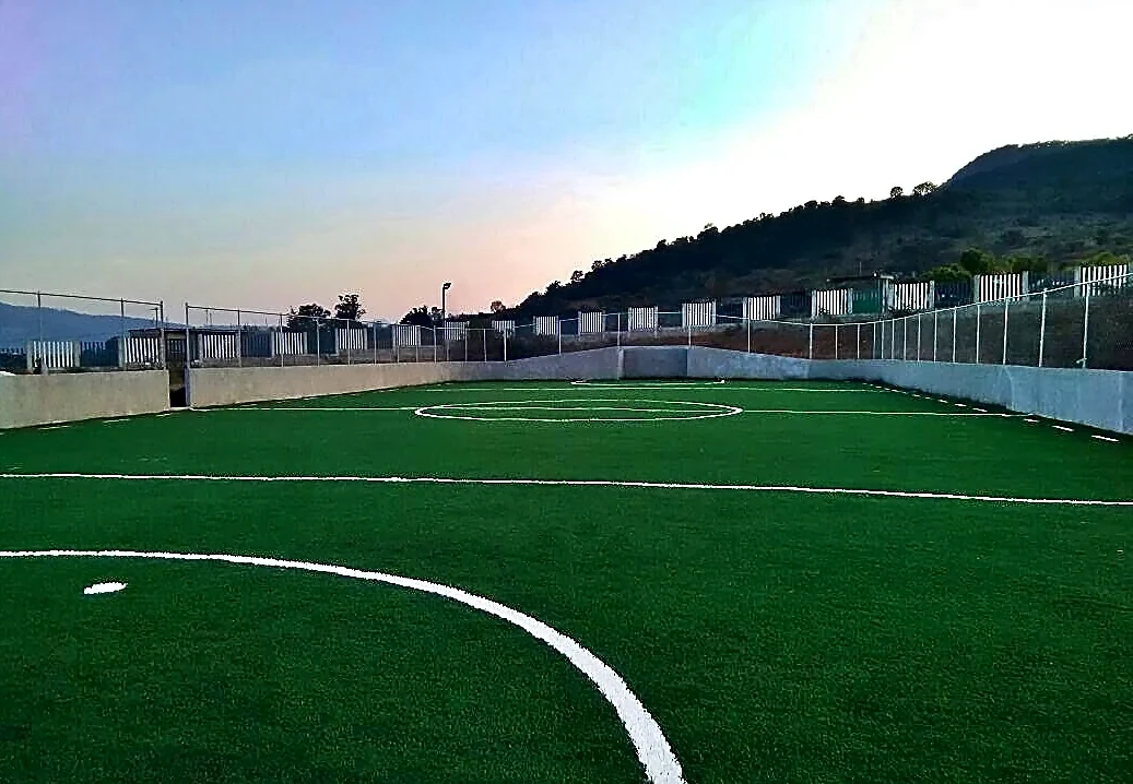 Cancha de fútbol rápido con pasto sintético en Unidad Deportiva Acuitzio del Canje, Michoacán: la cancha desde la línea lateral