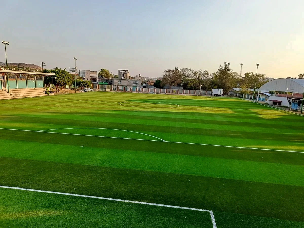 Cancha de fútbol soccer con pasto sintético en Unidad Deportiva Juárez, Benito Juárez, Michoacán: la cancha desde la línea lateral