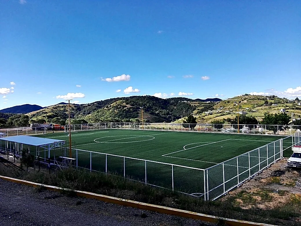 Cancha de fútbol soccer con pasto sintético en Campo Santiago Tamaozla, Tlaxiaco, Oaxaca: la cancha desde la línea lateral