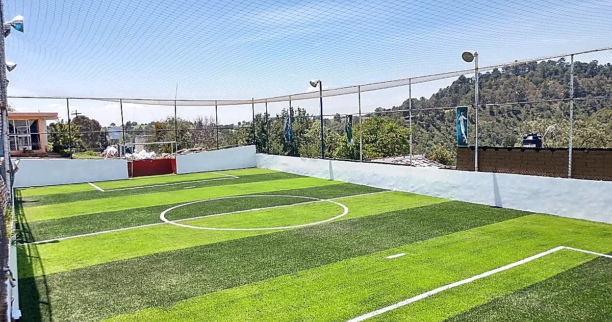 Cancha de fútbol 7 con pasto sintético en Campo Deportivo Titanes de Tlahuapan, Puebla: la cancha desde la línea lateral