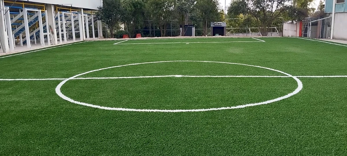 Cancha de fútbol 7 con pasto sintético en Escuela la Salle Juan Fromental Cayroche, San Francisco Totimehuacán, Puebla: líneas de juego insertadas en el mismo pasto