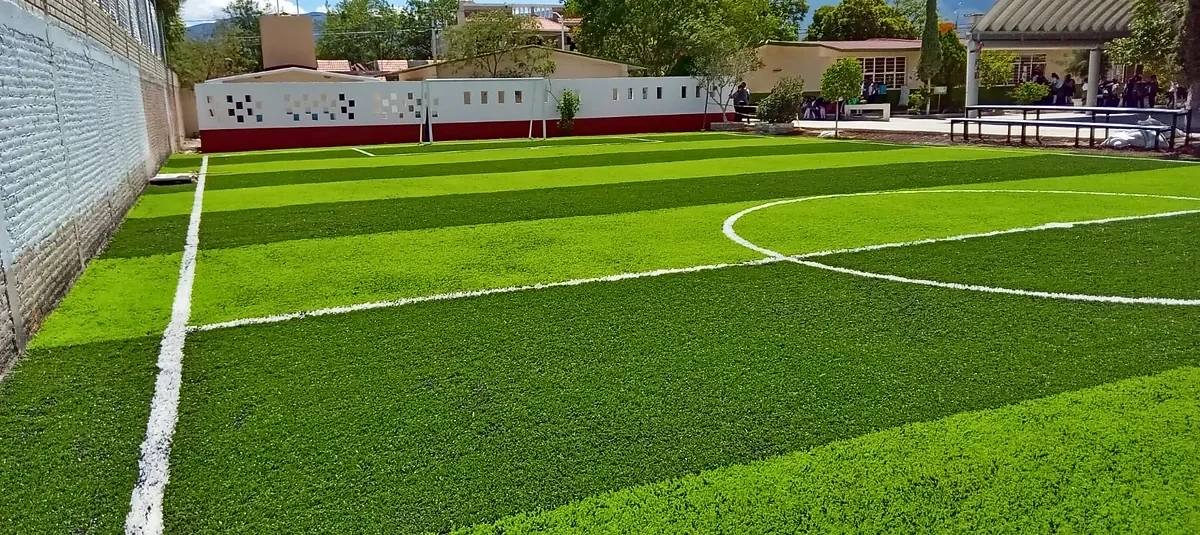 Cancha de fútbol 7 con pasto sintético en Telesecundaria Martín Luther King, San José Miahuatlán, Puebla: la cancha desde la línea lateral