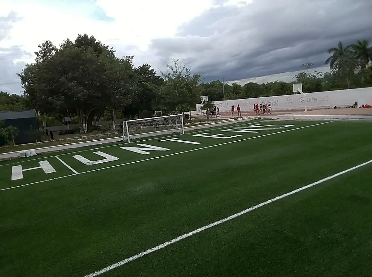 Campo de fútbol americano con pasto sintético en Colegio Álamos, Cancún, Quintana Roo: el campo desde la zona de anotación