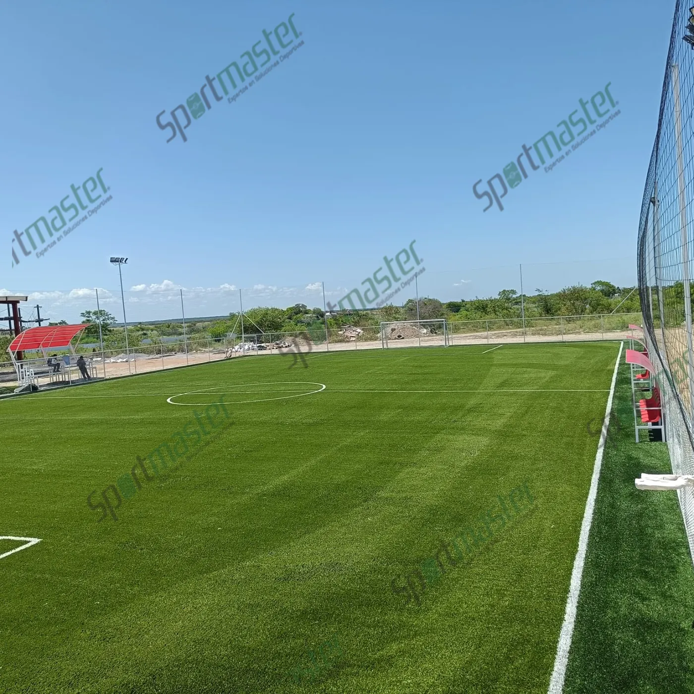 Cancha de fútbol 7 con pasto sintético y accesorios en UTMART, La Pesca, Soto La Marina, Tamaulipas: cancha vista desde la esquina, con cerco perimetral