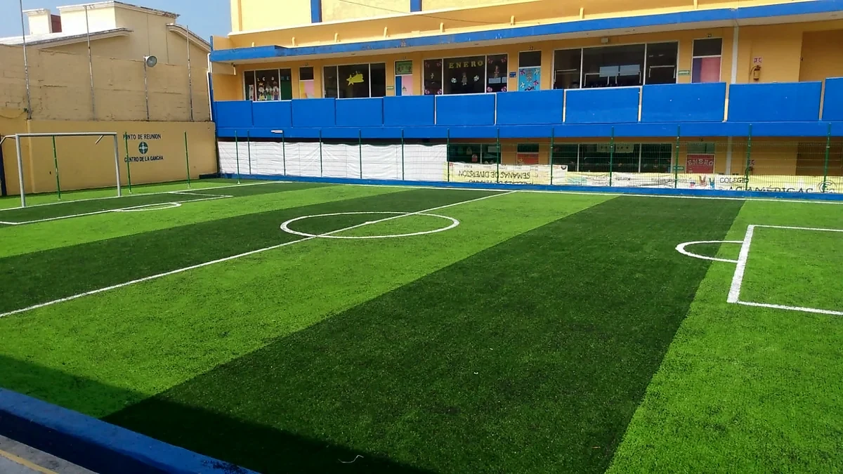 Cancha de fútbol 5 con pasto sintético en Colegio las Américas, Coatzacoalcos, Veracruz: la cancha desde la línea lateral